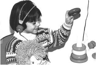 Παιγνιδοακοομετρία. Το εξεταζόμενο παιδί τοποθετεί ένα κρίκο στην πλαστική βάση, κάθε φορά που ακούει έναν ήχο από τα ακουστικά.